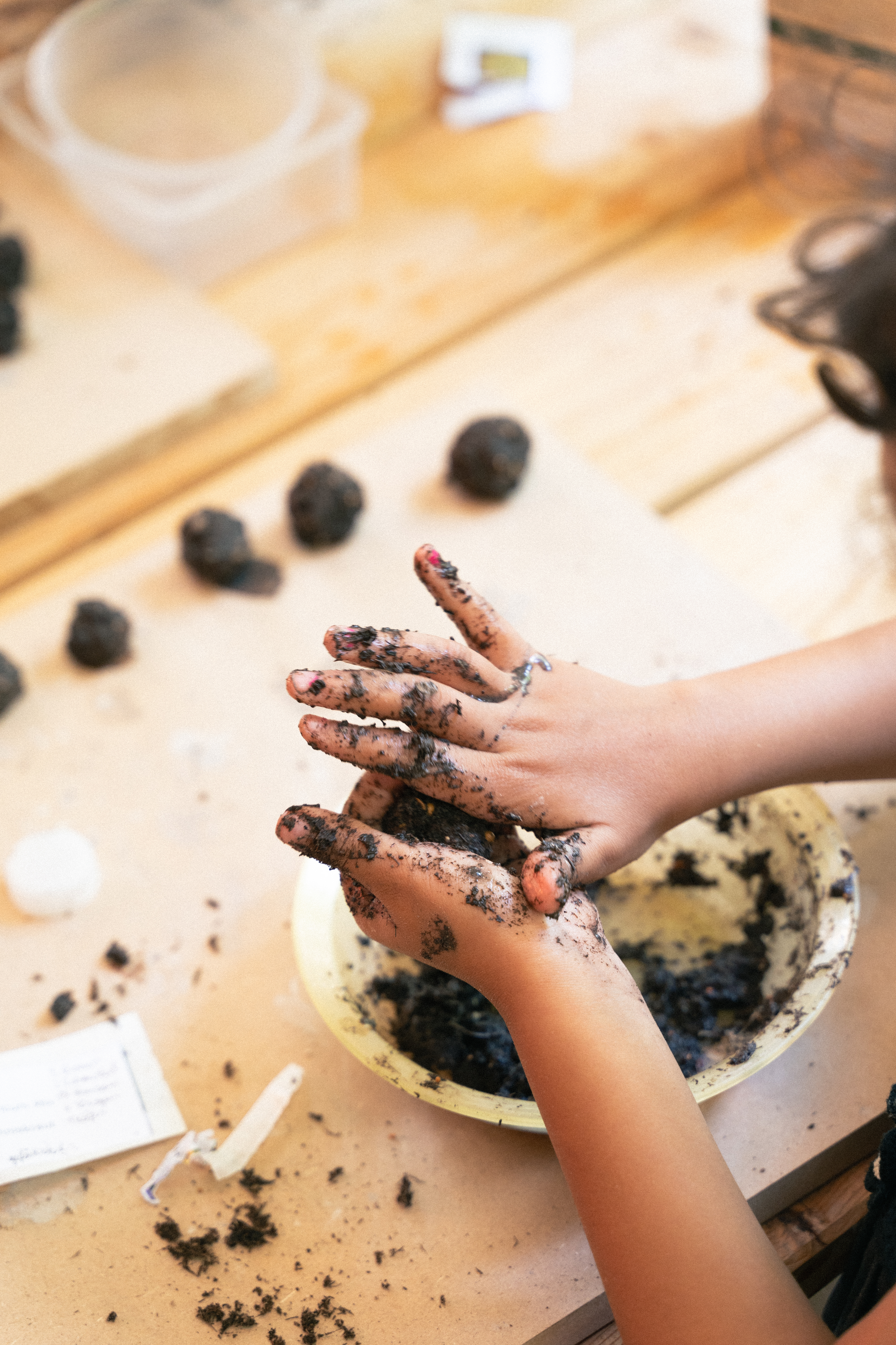 Kinderhände die aus Erde kleine Kugeln formen