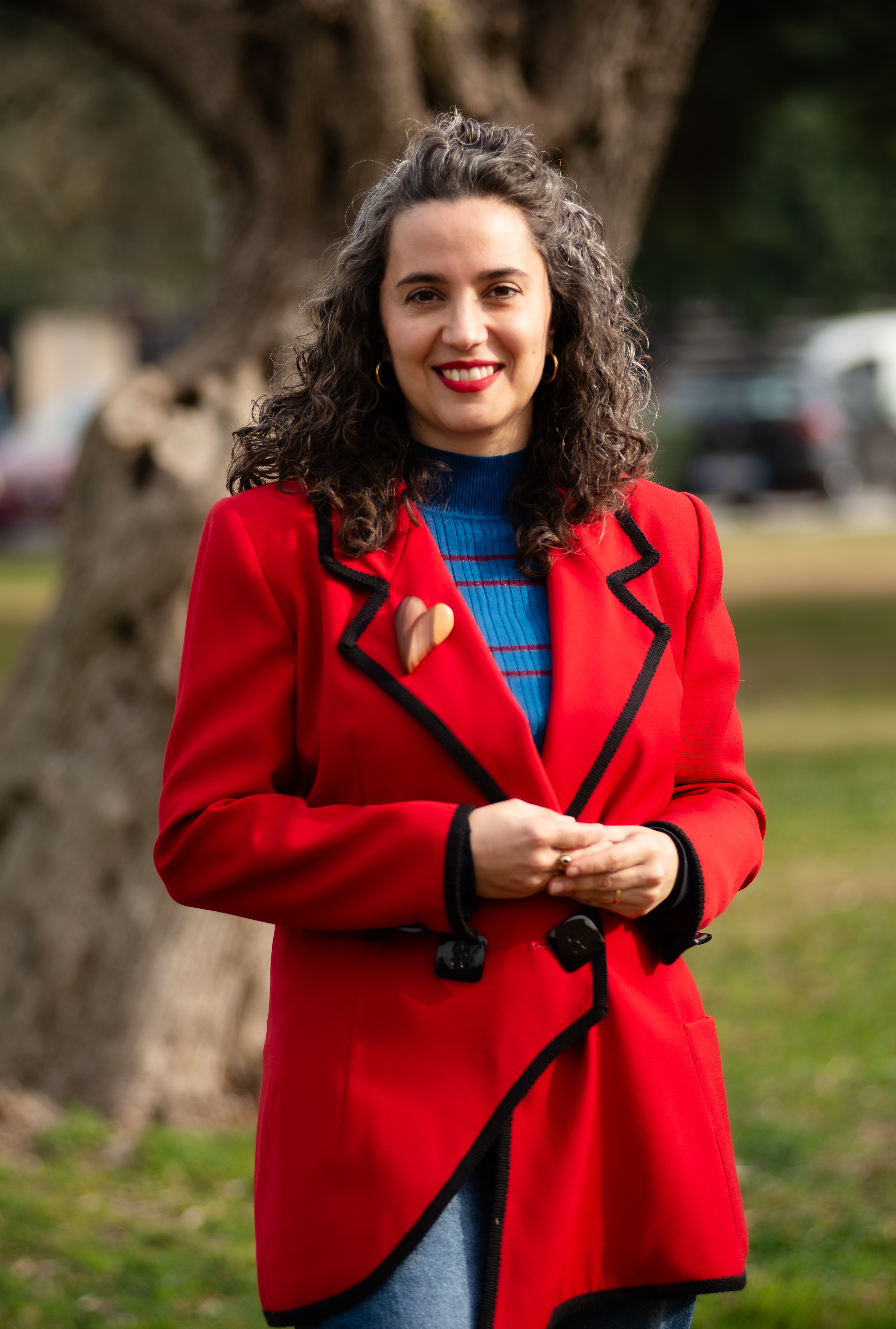 Frau mit roter Jacke und braunen Locken stehend auf einer Wiese