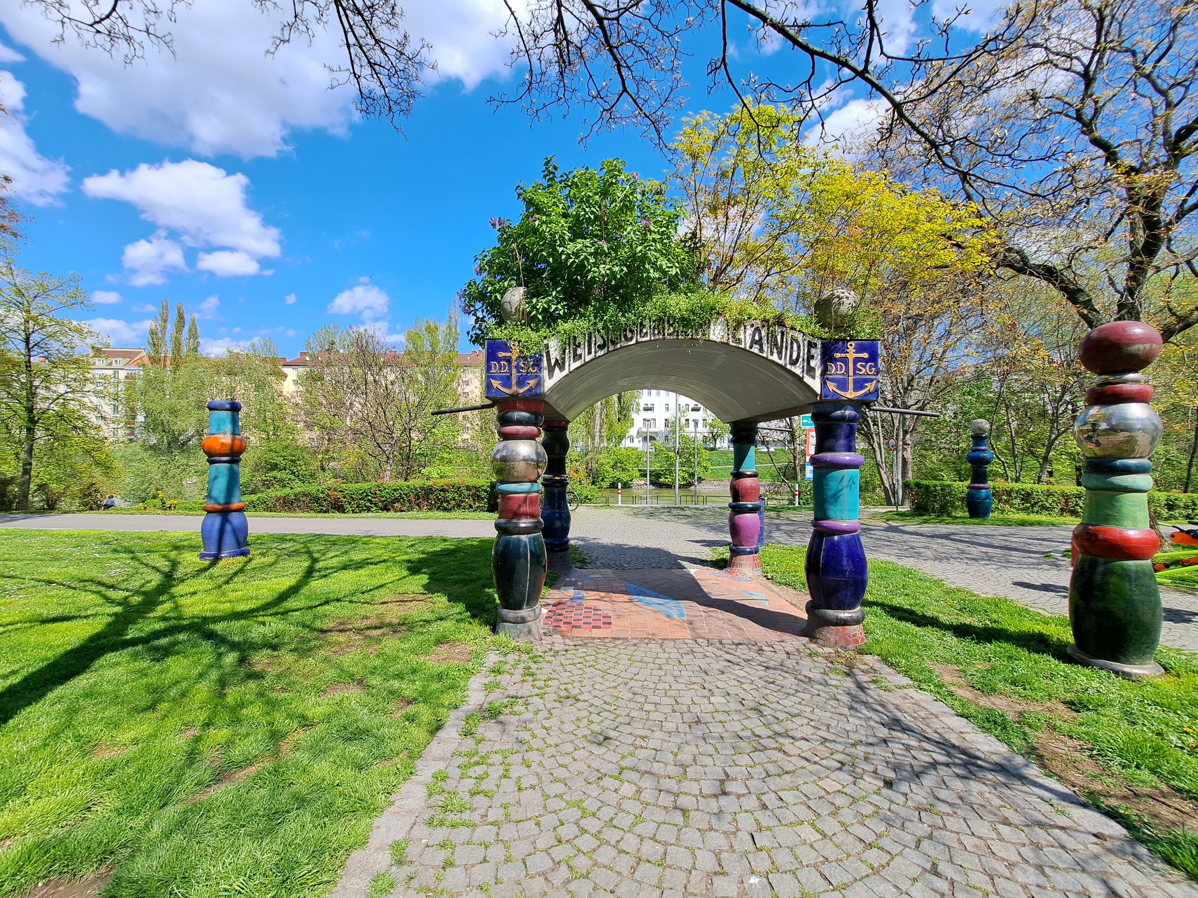 Colourful columns supporting a canopy on a grassy area next to the former pier.