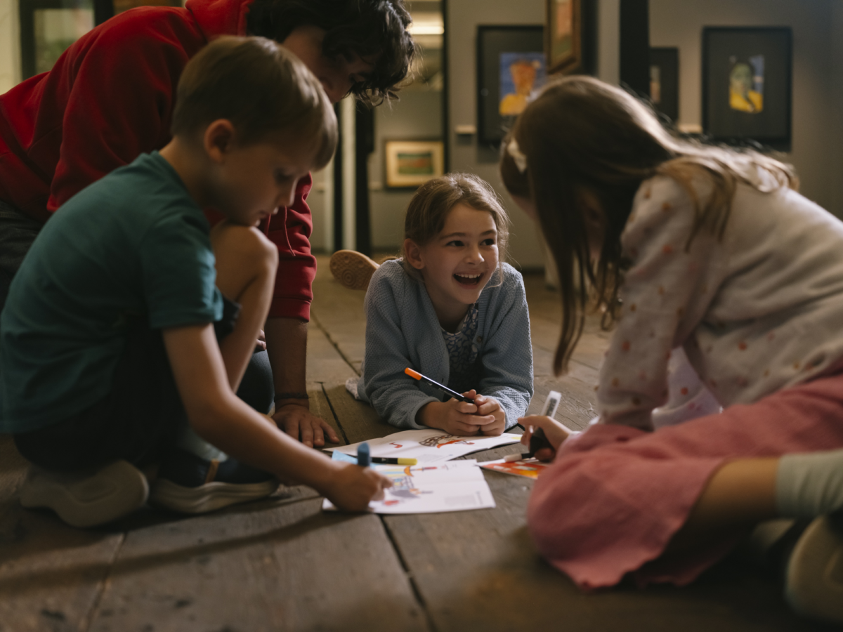 Kinder mit Buntstiften am Boden liegend