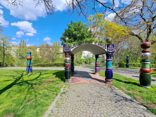Colourful columns supporting a canopy on a grassy area next to the former pier.