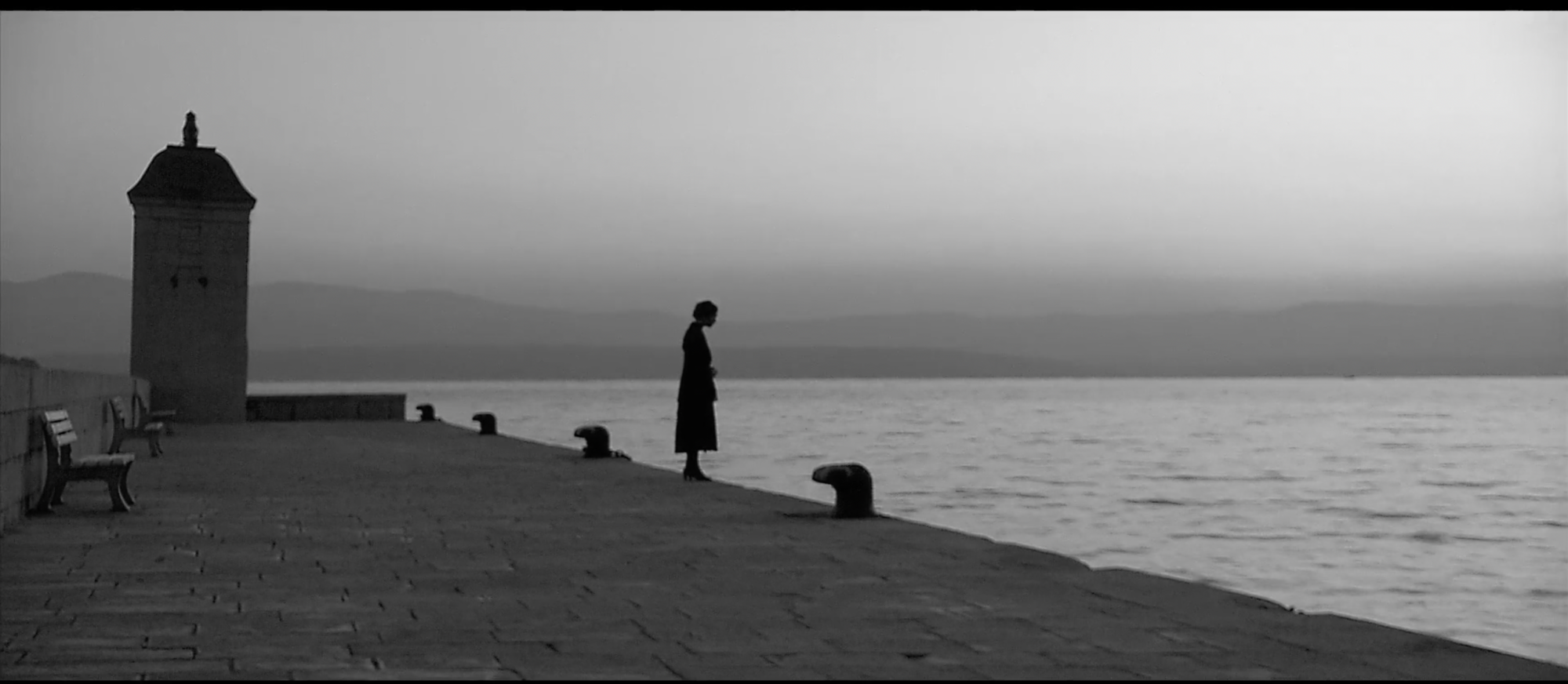 Schwarzweißbild von einer Person an einer Anlegestelle am Meer