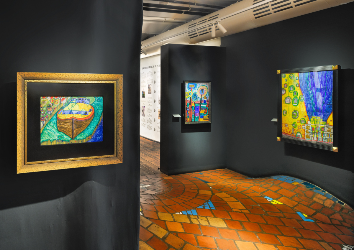 Einblick in die Ausstellung mit unebenen Boden und bunten Bildern an den Wänden