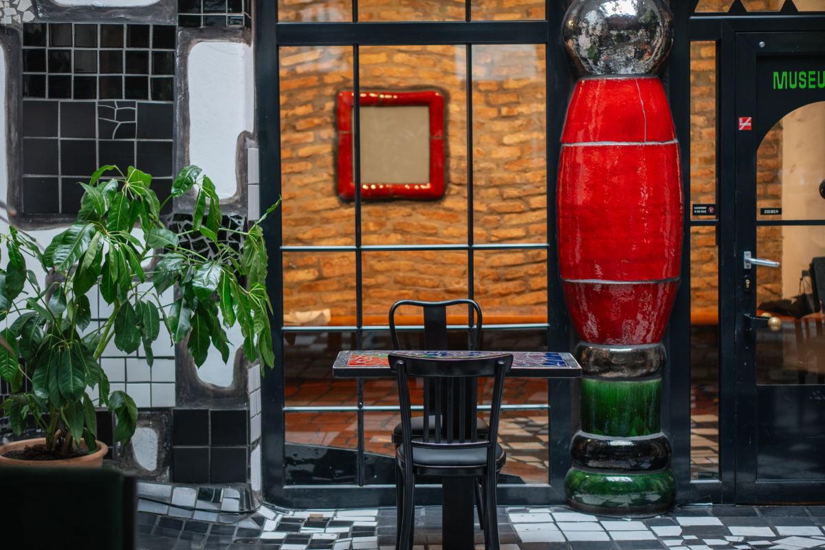 Cafehaustisch mit zwei Sessel, Glasfenster unterbrochen von einer roten Säule