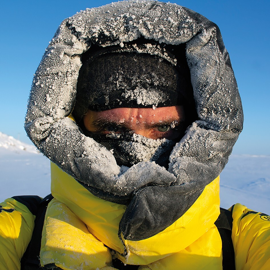 Selbstporträt des Künstlers Gregor Sailer, der einen Kapuzenmantel und eine Mütze trägt; nur seine Augen sind zu sehen