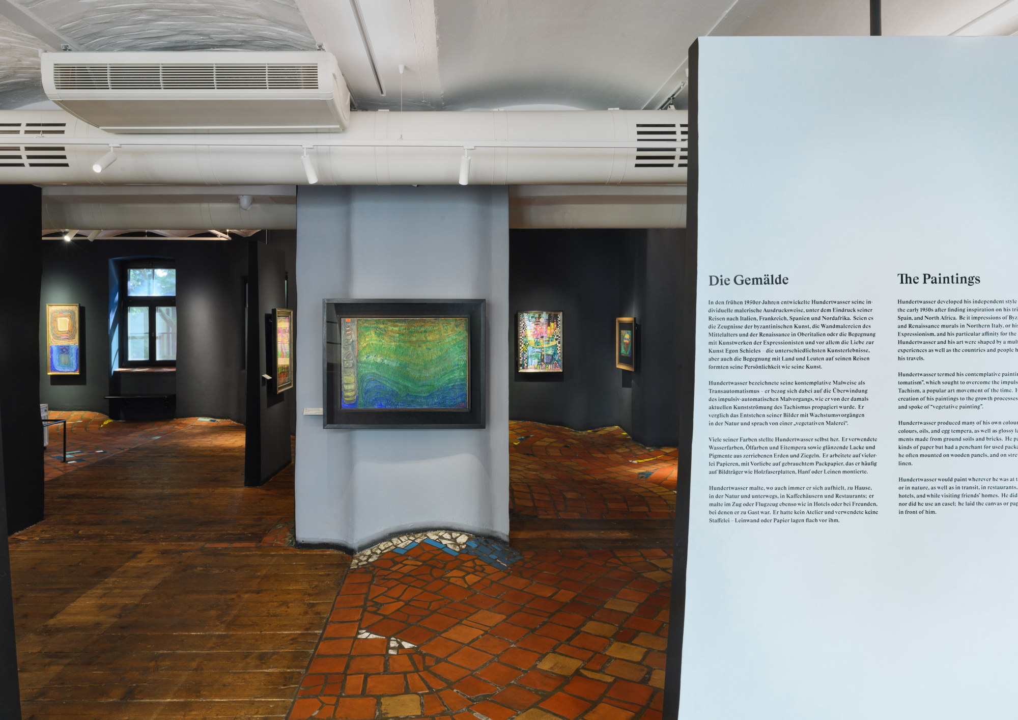 Einblick in den Ausstellungsraum mit unebenen Boden und Bildern an den Wänden