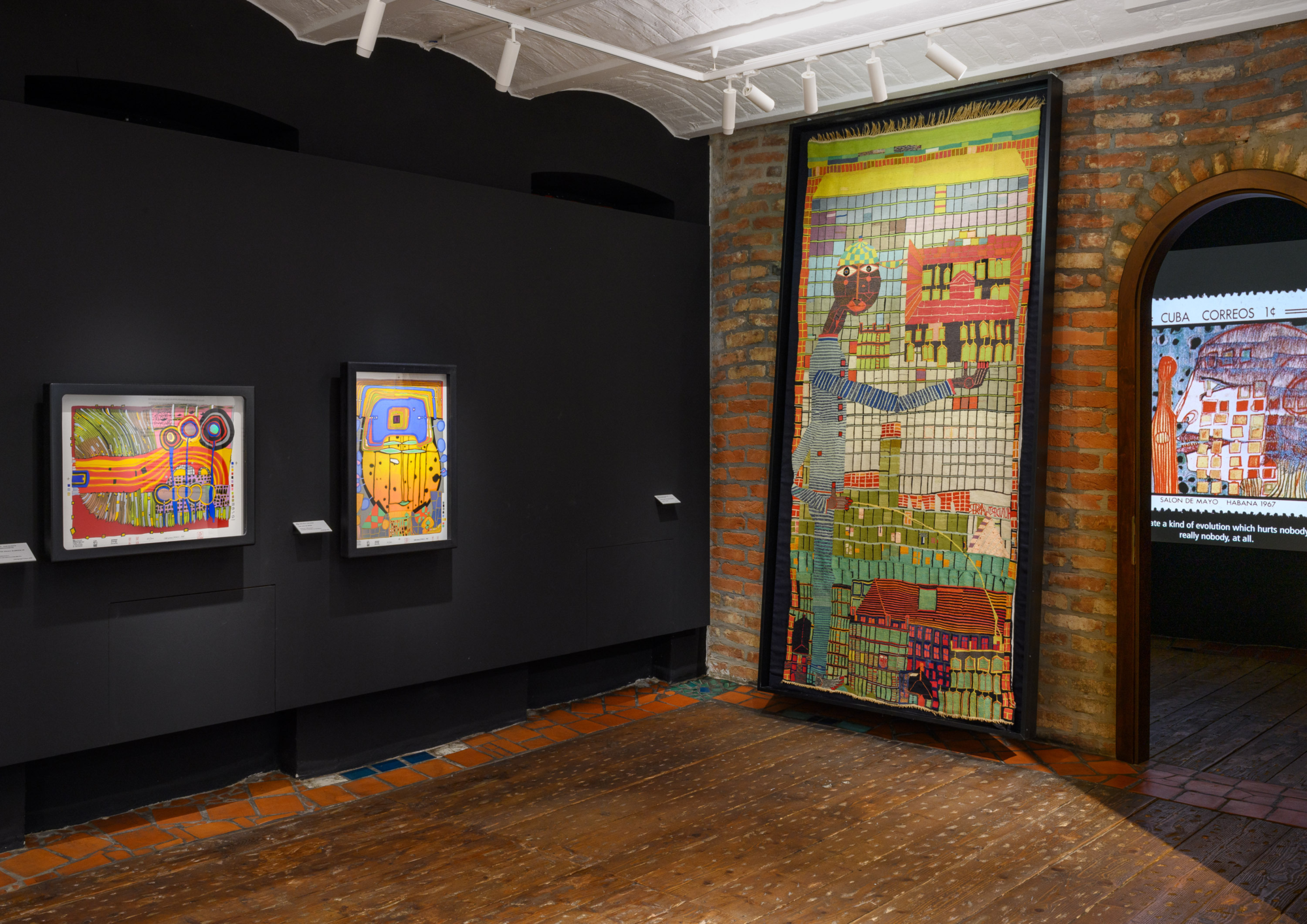 Bunte Bilder und eine Tapisserie auf schwarzen Wänden