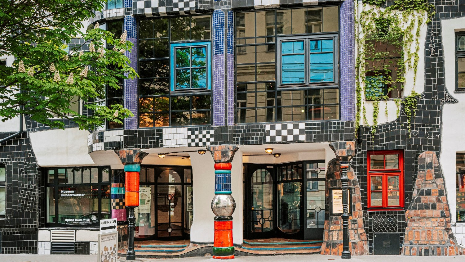 Fassade des KunstHausWien im Stil Hundertwassers. Schwarze und weiße Fliesen, bunte Säulen.