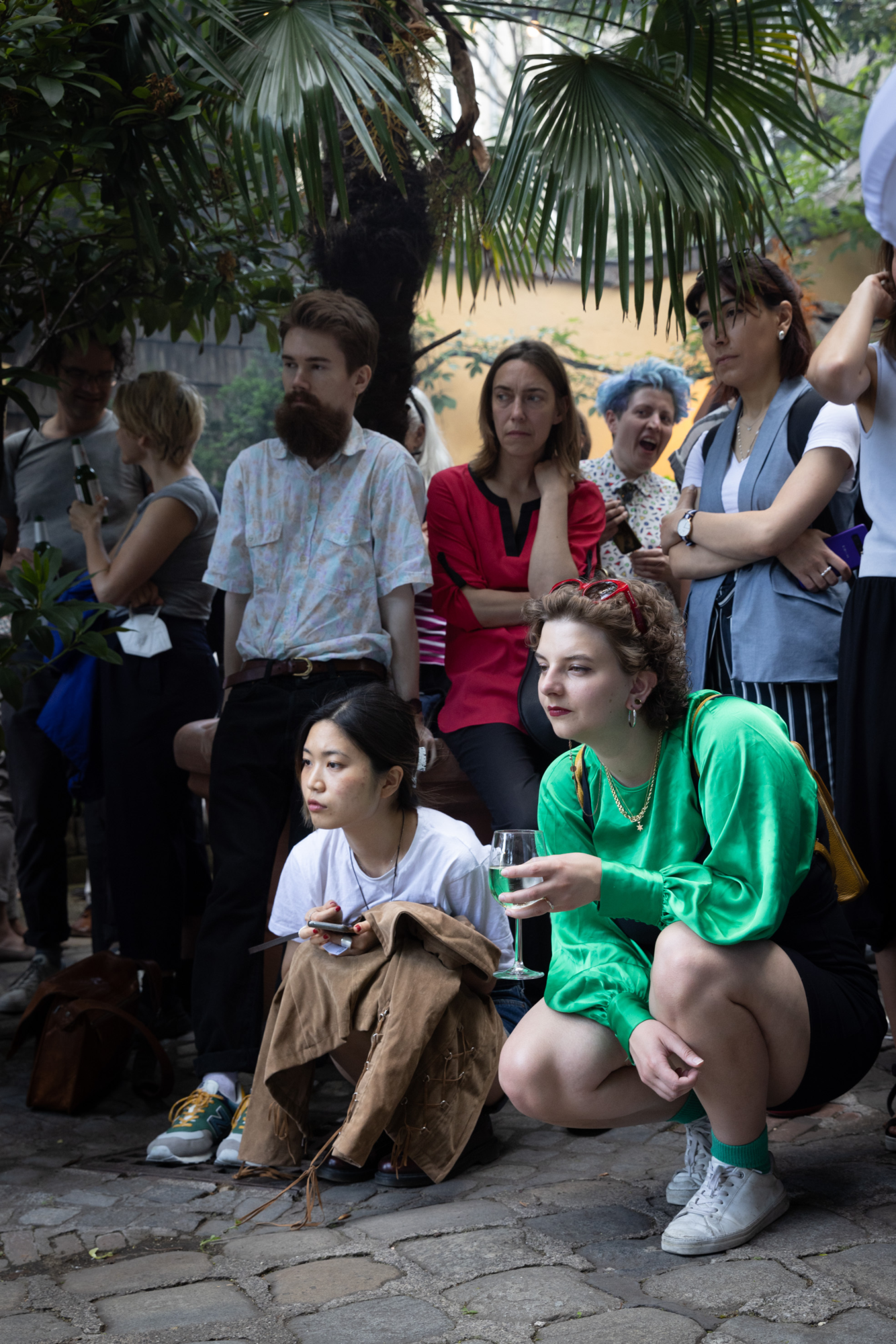Die Besucherinnen schauen sich eine Kunstperformance an die auf dem Foto nicht zu sehen ist.